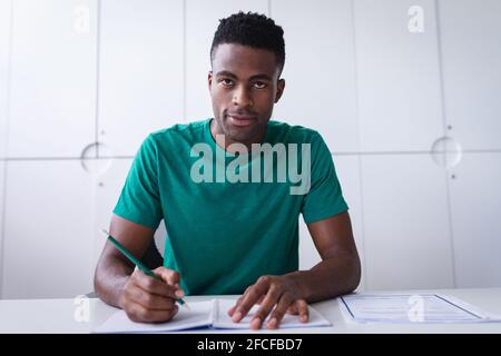 Glücklicher afrikanischer amerikanischer Geschäftsmann, der am Schreibtisch sitzt, während er einen Videoanruf Notizen machen Stockfoto