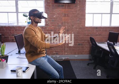 Afroamerikanischer Mann im Büro trägt Virtual Reality Set und Wiedergabe Stockfoto