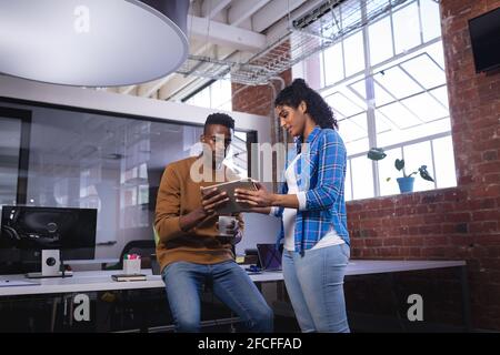 Verschiedene männliche und weibliche Kollegen bei der Arbeit stehen über diskutieren Kaffee und Tablet Stockfoto