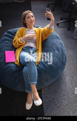 Geschäftsfrau mit gemischter Rasse, die im Büro chillt und sich entspannt in einem Raum herumliegt Sitzsack Stockfoto