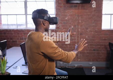 Afroamerikanischer Mann im Büro trägt Virtual Reality Set und Wiedergabe Stockfoto