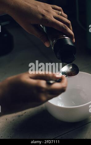 Instant-Kaffeepulver in eine Schüssel geben und den Löffel mit der Hand der Frauen halten. Zubereitung des Schneebesen in Schaum zur Zubereitung von Dalgona-Kaffee. Stockfoto