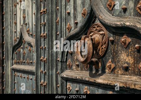 Details des Portals zur Kathedrale. Metallklopfer an schmiedeeisernen, verstärkten alten Holztüren zur Kathedrale von Girona, Spanien Stockfoto