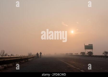 BAREILLY, UTTAR PRADESH, INDIEN - DEZEMBER 2020 : Indian Road Highways, wunderschöne Landschaft von indischen Straßen während Nebel und Sonnenaufgang im Wintermorgen. Stockfoto