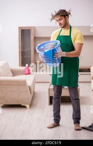 Junger männlicher Auftragnehmer, der auf dem Kopf einen stacheligen Kranz trägt und Hausarbeit leistet Stockfoto