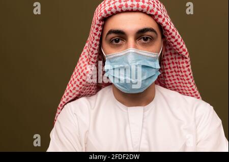 Muslimischer Mann, der eine medizinische Maske trägt. Porträt eines jungen arabischen Mannes in traditioneller Kleidung. Stockfoto