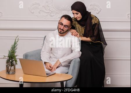 Muslimische Paare in nationaler Kleidung kommunizieren über Videokommunikation. Videokonferenz mit Freunden Stockfoto