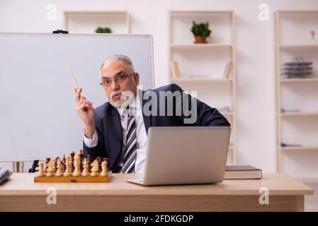 Alter Geschäftsmann Angestellter, der Schach am Arbeitsplatz spielt Stockfoto