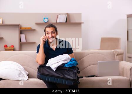 Junger Mann, der sich zu Hause auf die Reise vorbereitet Stockfoto
