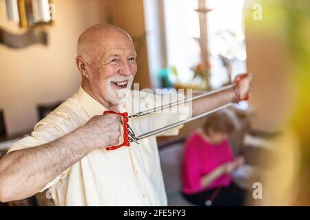 Älterer Mann, der im Wohnzimmer mit einem Brustaufweiler trainiert Stockfoto