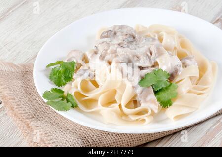 Fettuccine mit Pilzen in einer cremigen Sauce mit einem Kräuterzweig. Italienisches Gericht. Stockfoto