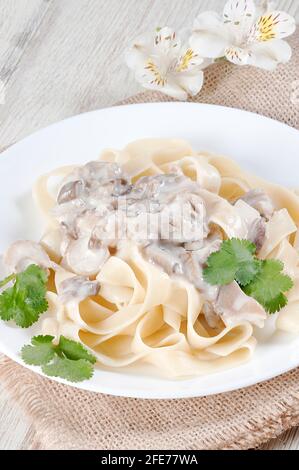 Fettuccine mit Pilzen in einer cremigen Sauce mit einem Kräuterzweig. Italienisches Gericht. Stockfoto