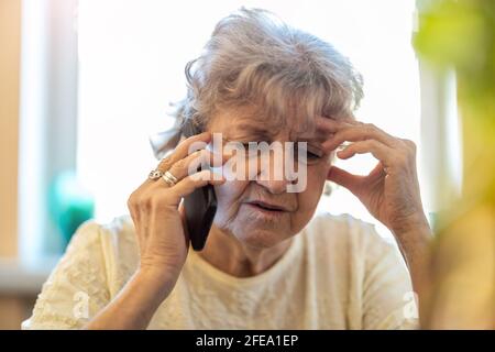 Aufnahme einer müden älteren Frau, die ein Mobiltelefon benutzt Stockfoto