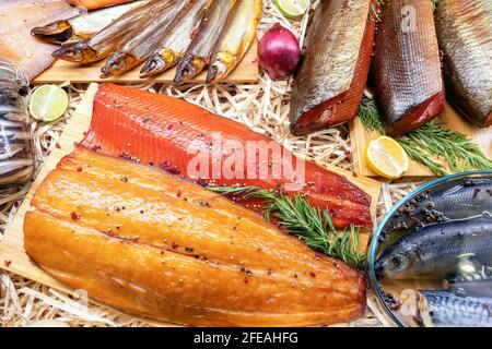 Geräucherte Lachsfilets und Pfeffer, Zitrone und Rosmarin auf Holzschneidebrett Draufsicht. Verschiedene Fische auf dem Fischmarkt. Fischhintergrund. Stockfoto