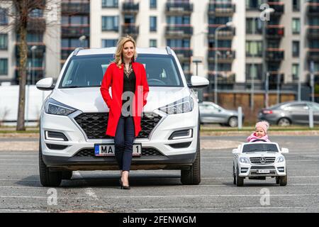 Riga, Lettland - 16. April 2021: Mutter und ihre kleine Tochter mit ihren weißen Autos, Konzept verschiedener Generationen Stockfoto