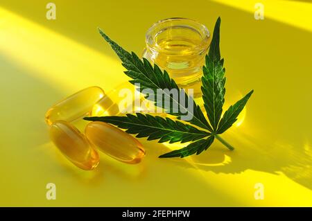 Marihuanaöl, CBD-Erholung. Frisches Cannabisblatt und medizinische Pillen auf gelbem Hintergrund, Draufsicht, Nahaufnahme. Entspannung zu Hause, Zeitvertreib-Therapie. Altern Stockfoto