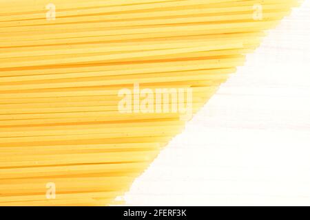 Ungekochte hellgelbe Spaghetti, aus der Nähe, auf einem bemalten Holztisch. Stockfoto