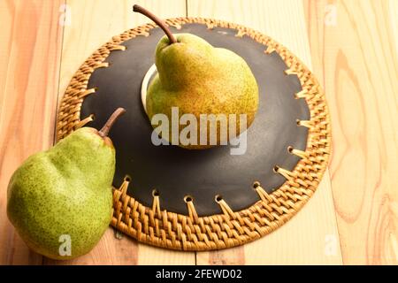 Zwei süße Birnen mit Keramikplatte, Nahaufnahme, auf einem Holztisch. Stockfoto