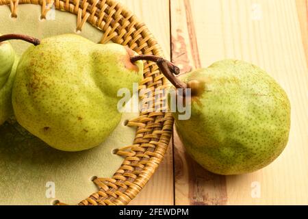 Zwei süße Birnen mit Keramikplatte, Nahaufnahme, auf einem Holztisch. Stockfoto