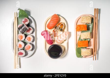 Sushi-Brötchen mit Reis und Fisch, Sojasauce auf weißem Hintergrund Stockfoto