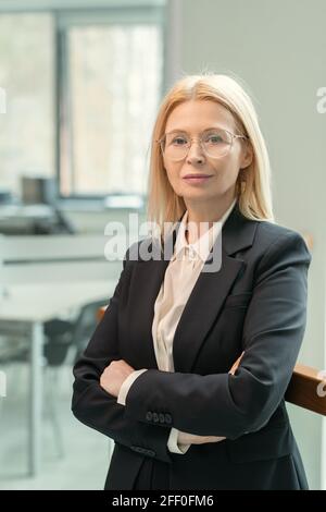 Porträt des Inhalts selbstbewusste weibliche Geschäftsführerin in schwarzer Jacke Überkreuzte Arme auf der Brust im modernen Büro Stockfoto
