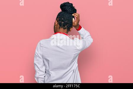 Junge afroamerikanische Frau mit Ärzteuniform und Stethoskop rückwärts Denken Sie an Zweifel mit Hand auf Kopf Stockfoto