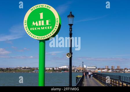 Eine Meile Markierung am Southend Pier an einem hellen sonnigen Tag in Southend on Sea, Essex, Großbritannien. 1 Meile Wegweiser, mit Leuten, die den Weg gehen Stockfoto