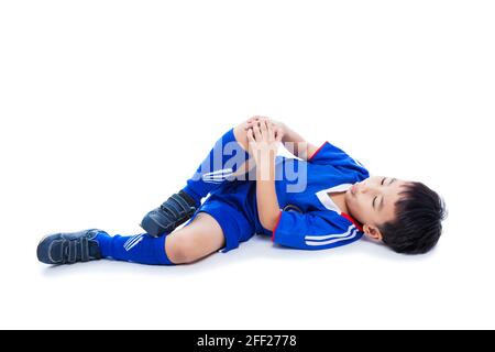 Sportverletzung. Junger asiatischer (thailändischer) Fußballspieler in blauer Uniform mit Knieschmerzen. Isoliert auf weißem Hintergrund. Studioaufnahme. Ganzkörper. Junge, lege dich hin. Stockfoto