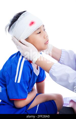 Sportverletzung. Athlet kleiner asiatischer (thailändischer) Junge in blauer Sportkleidung mit Trauma des Kopfes, blutig auf Verband. Der Arzt macht einen Verband am Kopfpatienten, Stockfoto