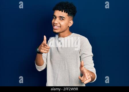 Junge afroamerikanische Mann trägt Freizeitkleidung zeigt Finger zur Kamera mit glücklichen und lustigen Gesicht. Gute Energie und Vibes. Stockfoto