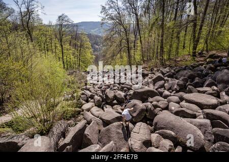 Lautertal, Deutschland. April 2021. Im Sonnenschein klettern die Besucher über die großen Felsen des Felsenmeers bei Lautertal. Die felsige Landschaft ist ein beliebtes Ausflugsziel im Odenwald. Kredit: Frank Rumpenhorst/dpa/Alamy Live Nachrichten Stockfoto