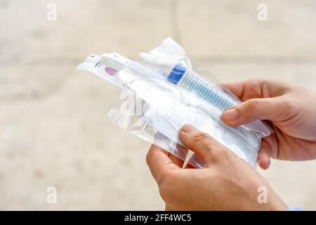 Nahaufnahme eines asiatischen Mannes hält das Coronavirus-Testkit auf dem Außenfeld in der Hand. Stockfoto