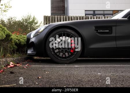 Die vordere Hälfte eines Satin Black 2015 Mercedes AMG GTS mit AMG Gloss Black Wheels mit Center Locking Cap Und Bremssättel der Marke Red AMG Stockfoto