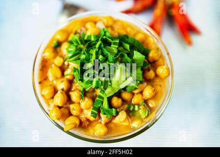 Gekochte Kichererbsen mit grünen Trieben, roter Pfeffer auf blauem Hintergrund, Nahaufnahme, Draufsicht. Stockfoto