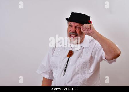 Blick auf einen älteren Mann in einem Hut, der ihn kratzt Kopf versucht, sich auf einem weißen Hintergrund zu erinnern Stockfoto
