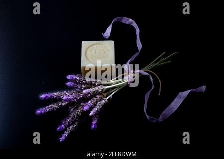 Ein Stück Seife, das auf Französisch geschrieben hat: „reines Gemüse, 125 Gramm, Made in France“ mit einem Bouquet von Lavendelblüten, gebunden mit cremefarbenem Seil und Stockfoto