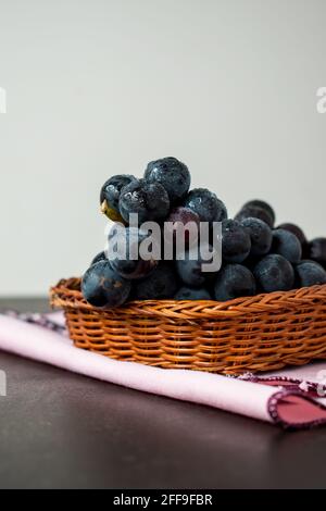 Einige Trauben in Körben auf einem schwarzen Tisch mit Ein weißer Hintergrund Stockfoto