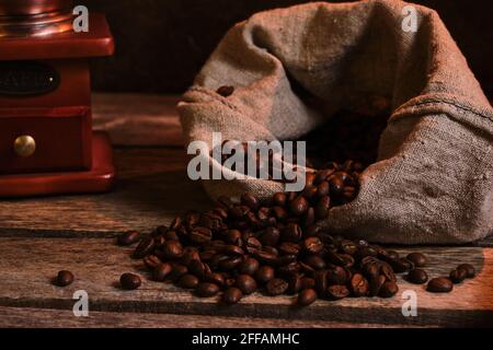 Geröstete Kaffeebohnen im Beutel und Kaffeemühle auf einem Alter Holztisch Stockfoto