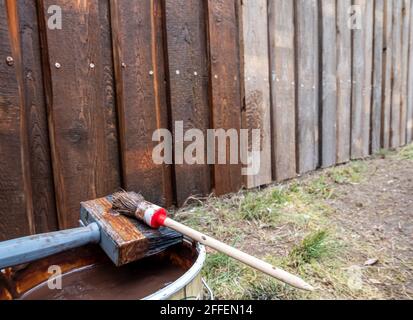 Eimer mit Pinsel auf einen Holzzaun streichen Stockfoto