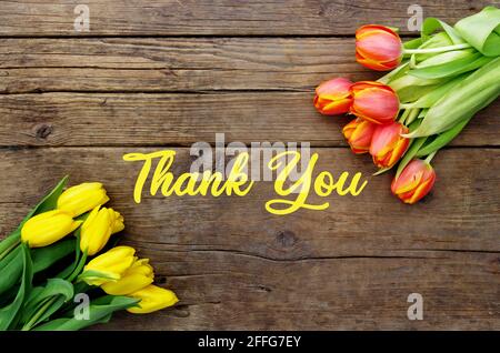 Dankesnachricht, bunte Tulpen auf Holzhintergrund. Frühling Blume Hintergrund mit blühenden Tulpen.Muttertag Grußkarte Feier. Stockfoto