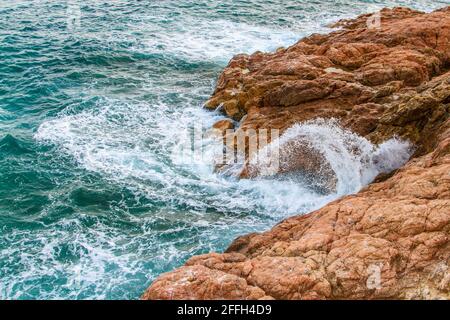 Tidalbohrung. Schaumig blaue Wellen krachen auf Küstenklippen. Stockfoto