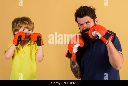 Kindersportler beim Boxtraining mit Trainer. Bereit zum Sparring. Bärtiger Sportmann, der einen kleinen Jungen beim Boxen trainierte. Stockfoto