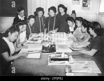 Frau Ryie Yoshizawa, Lehrerin für Mode und Design, mit einer Gruppe von Studenten, die sich mit Modemagazinen und Mustern beschäftigt, Manzanar Relocation Center, Kalifornien, USA, Ansel Adams, Manzanar War Relocation Center Collection, 1943 Stockfoto