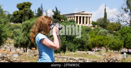 Mädchen Tourist macht Foto von Athen, Griechenland, Europa. Tempel des Hephaestus, Wahrzeichen von Athen in der Ferne. Junge hübsche Frau fotografiert Attraktionen o Stockfoto