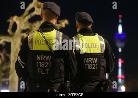 Düsseldorf, Deutschland. April 2021. Polizeibeamte stehen auf der Rheinpromenade, im Hintergrund der Rheinturm. Seit April 24 die Regelung einer bundesweiten Corona-Notbremse. Dazu gehören unter anderem Sperrungen zwischen 22 und 5 Uhr. Kredit: David Young/dpa/Alamy Live Nachrichten Stockfoto