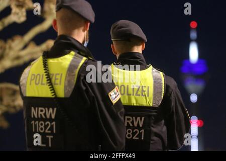 Düsseldorf, Deutschland. April 2021. Polizeibeamte stehen auf der Rheinpromenade, im Hintergrund der Rheinturm. Seit April 24 die Regelung einer bundesweiten Corona-Notbremse. Dazu gehören unter anderem Sperrungen zwischen 22 und 5 Uhr. Kredit: David Young/dpa/Alamy Live Nachrichten Stockfoto