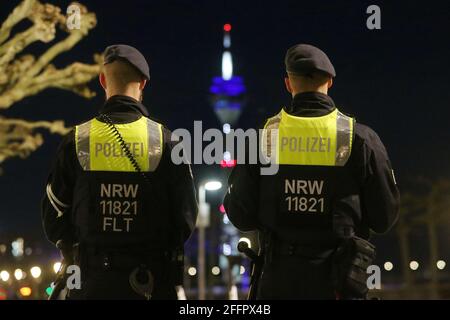 Düsseldorf, Deutschland. April 2021. Polizeibeamte stehen auf der Rheinpromenade, im Hintergrund der Rheinturm. Seit April 24 die Regelung einer bundesweiten Corona-Notbremse. Dazu gehören unter anderem Sperrungen zwischen 22 und 5 Uhr. Kredit: David Young/dpa/Alamy Live Nachrichten Stockfoto