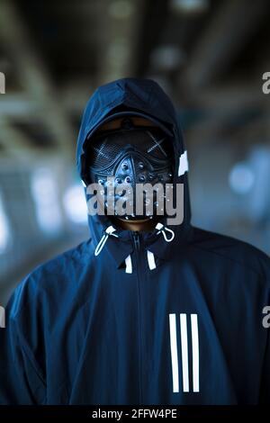 Schwarze Maske mit Nieten auf schwarzem Kapuzenpulli gekleideten Mann Stockfoto