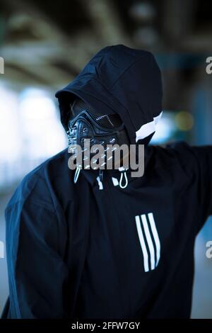 Schwarze Maske mit Nieten auf schwarzem Kapuzenpulli gekleideten Mann Stockfoto