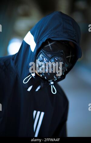 Schwarze Maske mit Nieten auf schwarzem Kapuzenpulli gekleideten Mann Stockfoto